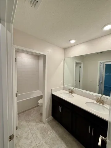 a bathroom with a double vanity sink toilet mirror and bathtub
