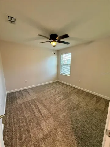 an empty room with a window and a ceiling fan