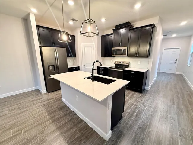 a kitchen with stainless steel appliances a sink a refrigerator and microwave