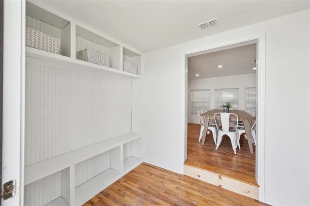 a kitchen with stainless steel appliances granite countertop a stove top oven a sink a dining table and chairs with wooden floor