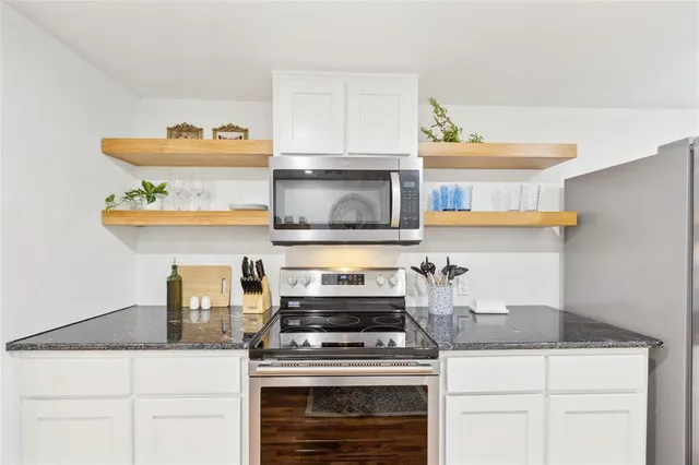 a kitchen with a sink and a stove with white cabinets