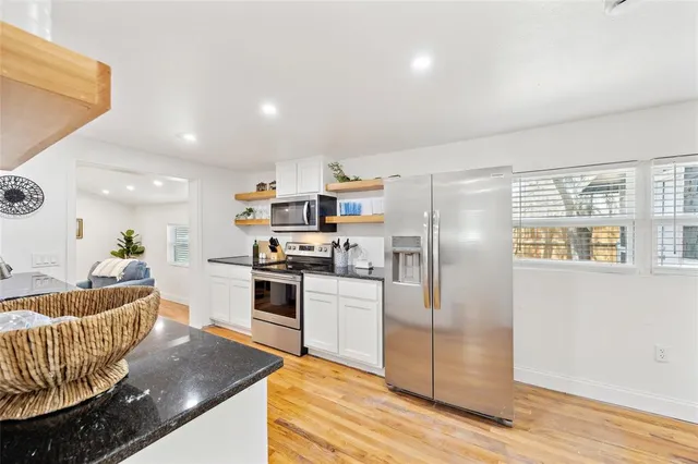 a living room with stainless steel appliances furniture and a wooden floor