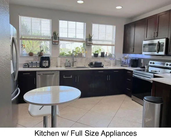a kitchen with stainless steel appliances kitchen island granite countertop a sink dishwasher a stove a refrigerator with a dining table and chairs