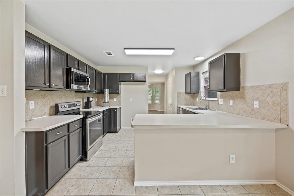 3931 Alpha Way Midlothian, TX 76065 - Photo 14 of 33 a kitchen with stainless steel appliances granite countertop a sink and a refrigerator