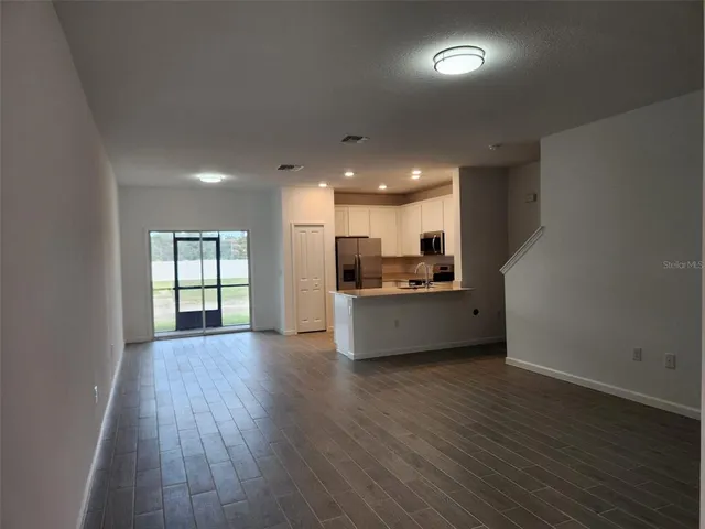 a kitchen with stainless steel appliances kitchen island wooden floors and view living room