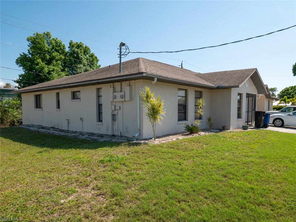 19029-19031 Holly Road Fort Myers, FL 33967 - Photo 3 of 15 View of side of home featuring stucco siding, a yard, and roof with shingles