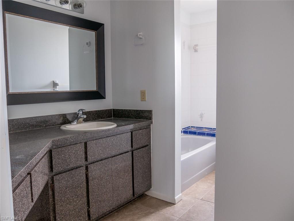 19029-19031 Holly Road Fort Myers, FL 33967 - Photo 9 of 15 Full bath with vanity, light tile patterned floors, and washtub / shower combination