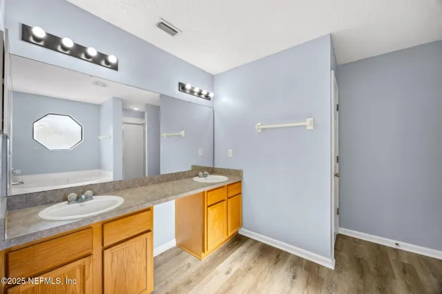a bathroom with a granite countertop double vanity sink and mirror