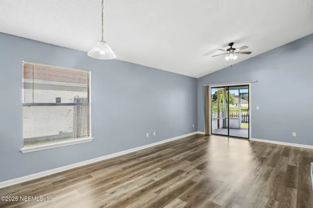a view of an empty room with a window and wooden floor