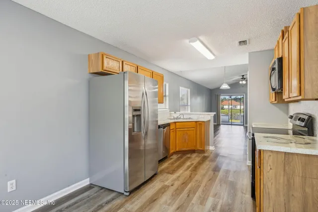 a view of a kitchen with a refrigerator a sink wooden floor and a window
