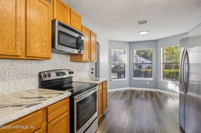 a kitchen with stainless steel appliances granite countertop a stove a sink and a microwave