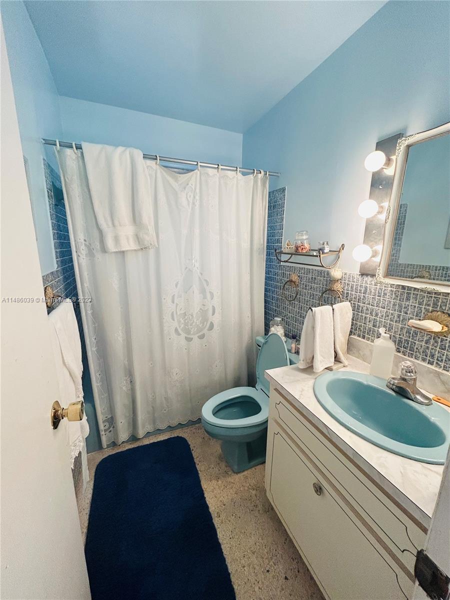 2311 Southwest 23rd Street Miami, FL 33145 - Photo 17 of 21 a bathroom with a sink a toilet a mirror and shower curtain