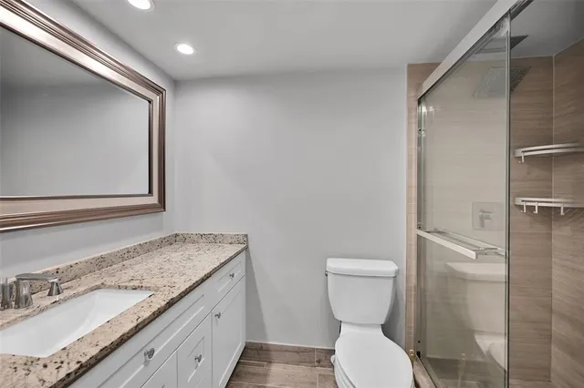 a bathroom with a granite countertop toilet sink and mirror