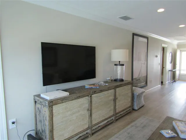 a living room with stainless steel appliances furniture and a flat screen tv