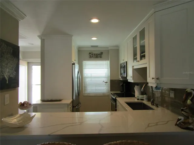 a living room with stainless steel appliances kitchen island granite countertop furniture a rug and a window