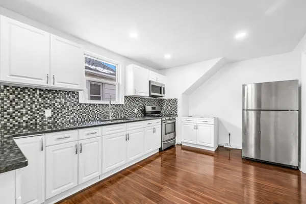 a kitchen with granite countertop white cabinets and white appliances