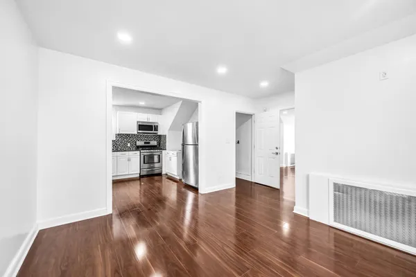 a view of an empty room with wooden floor and a cabinet