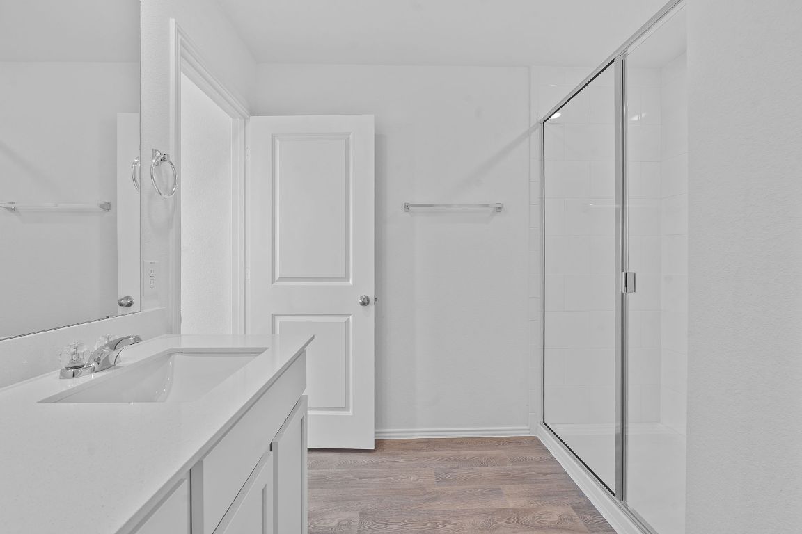 13309 Mancos Shale Road Mustang Ridge, TX 78610 - Photo 11 of 19 Bathroom featuring vanity, light wood-type flooring, and a stall shower