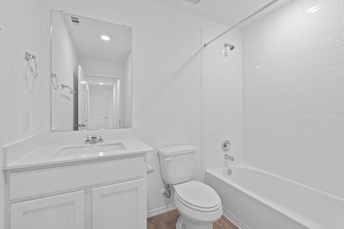13309 Mancos Shale Road Mustang Ridge, TX 78610 - Photo 14 of 19 Bathroom with tub / shower combination, vanity, and dark wood finished floors