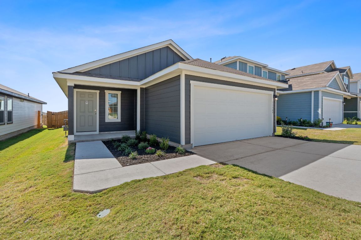 13309 Mancos Shale Road Mustang Ridge, TX 78610 - Photo 19 of 19 View of front facade with board and batten siding, driveway, and a garage