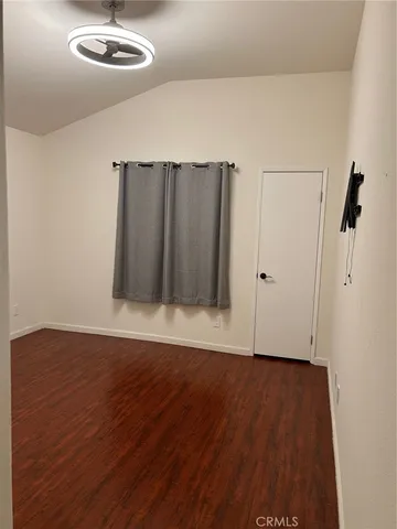 an empty room with wooden floor chandelier fan and windows