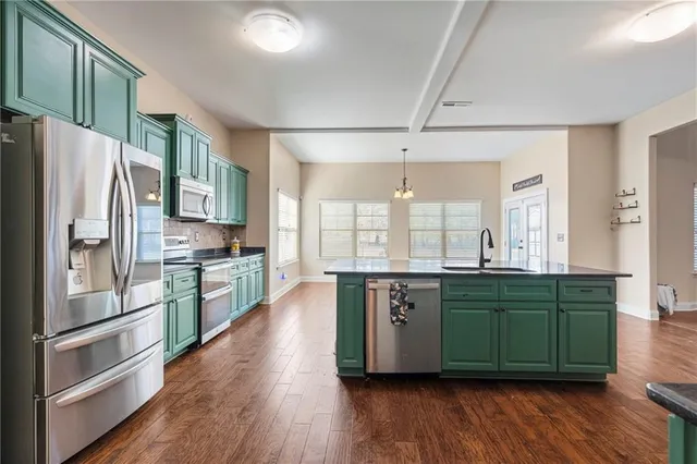 a kitchen with stainless steel appliances granite countertop a refrigerator a sink dishwasher a stove and white cabinets with wooden floor