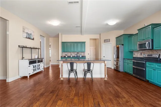 a kitchen with stainless steel appliances a dining table chairs stove microwave and cabinets