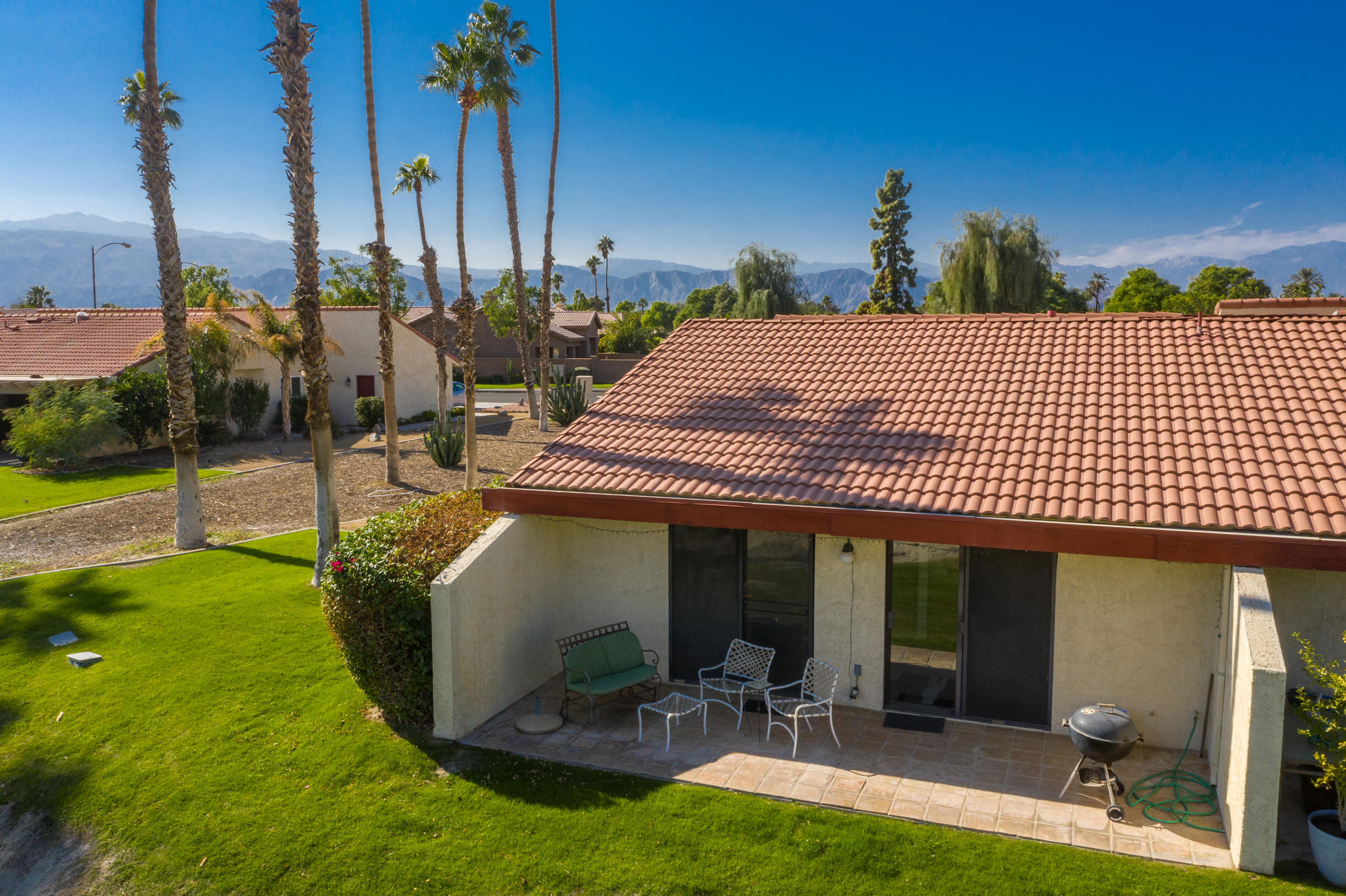 49058 Wayne Street Indio, CA 92201 - Photo 12 of 26 a view of a patio with table and chairs potted plants and palm tree