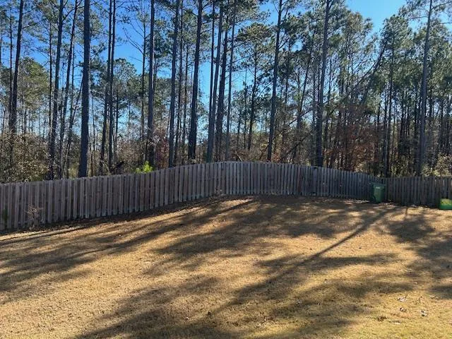 a view of a backyard with trees and wooden fence