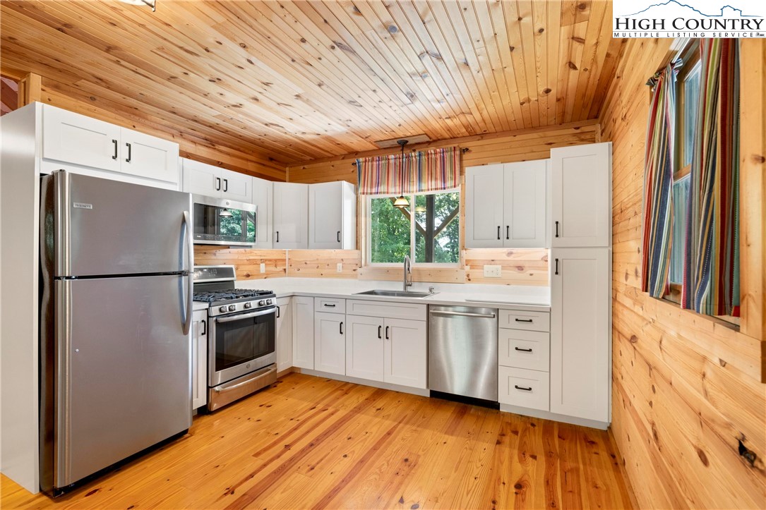 207 Carters Lane Purlear, NC 28665 - Photo 8 of 50 a kitchen with stainless steel appliances granite countertop a refrigerator a sink dishwasher a stove and white countertops with wooden floor