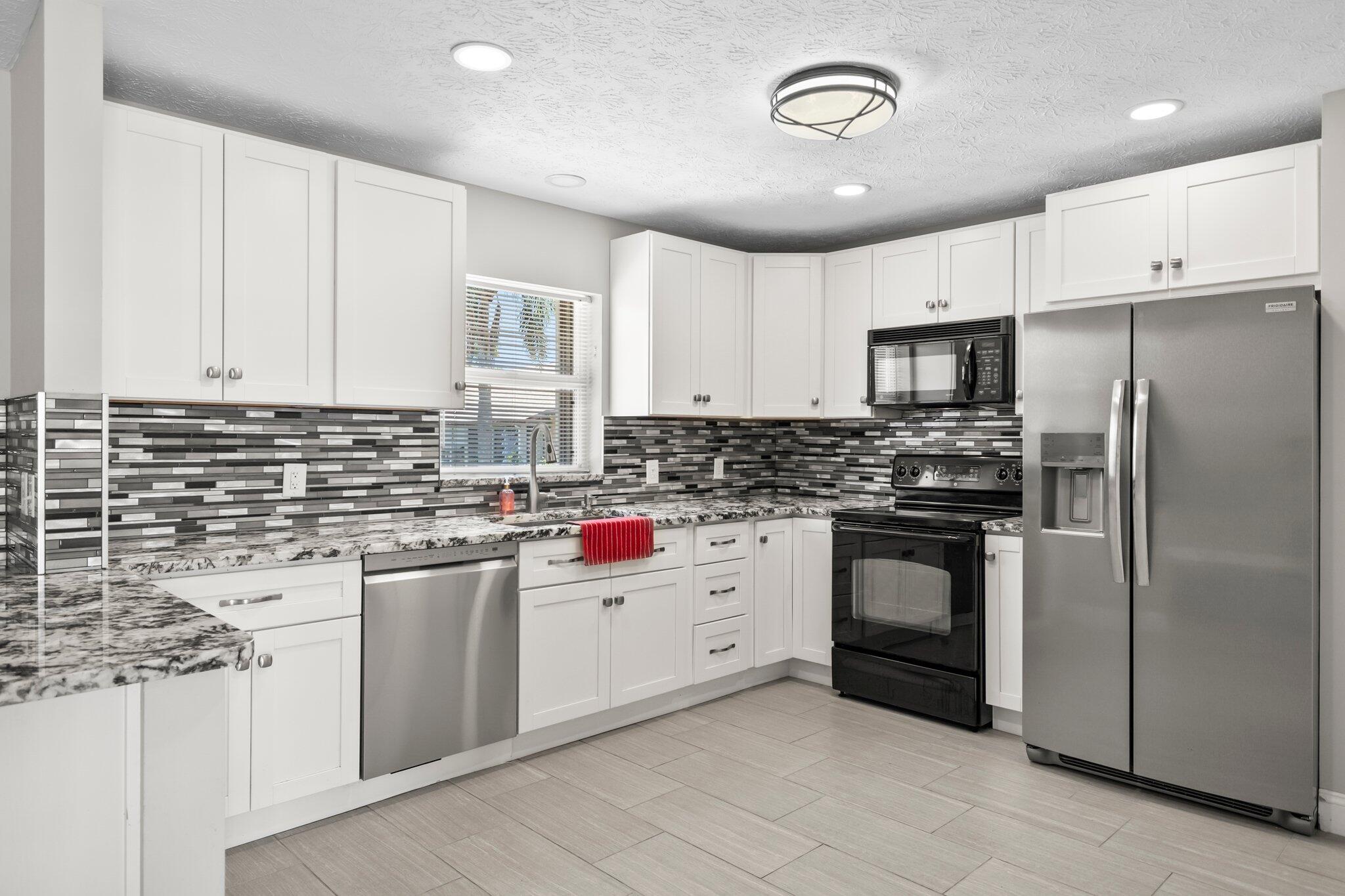 5712 Spindle Place Fort Pierce, FL 34982 - Photo 9 of 35 a kitchen with stainless steel appliances granite countertop a sink and cabinets