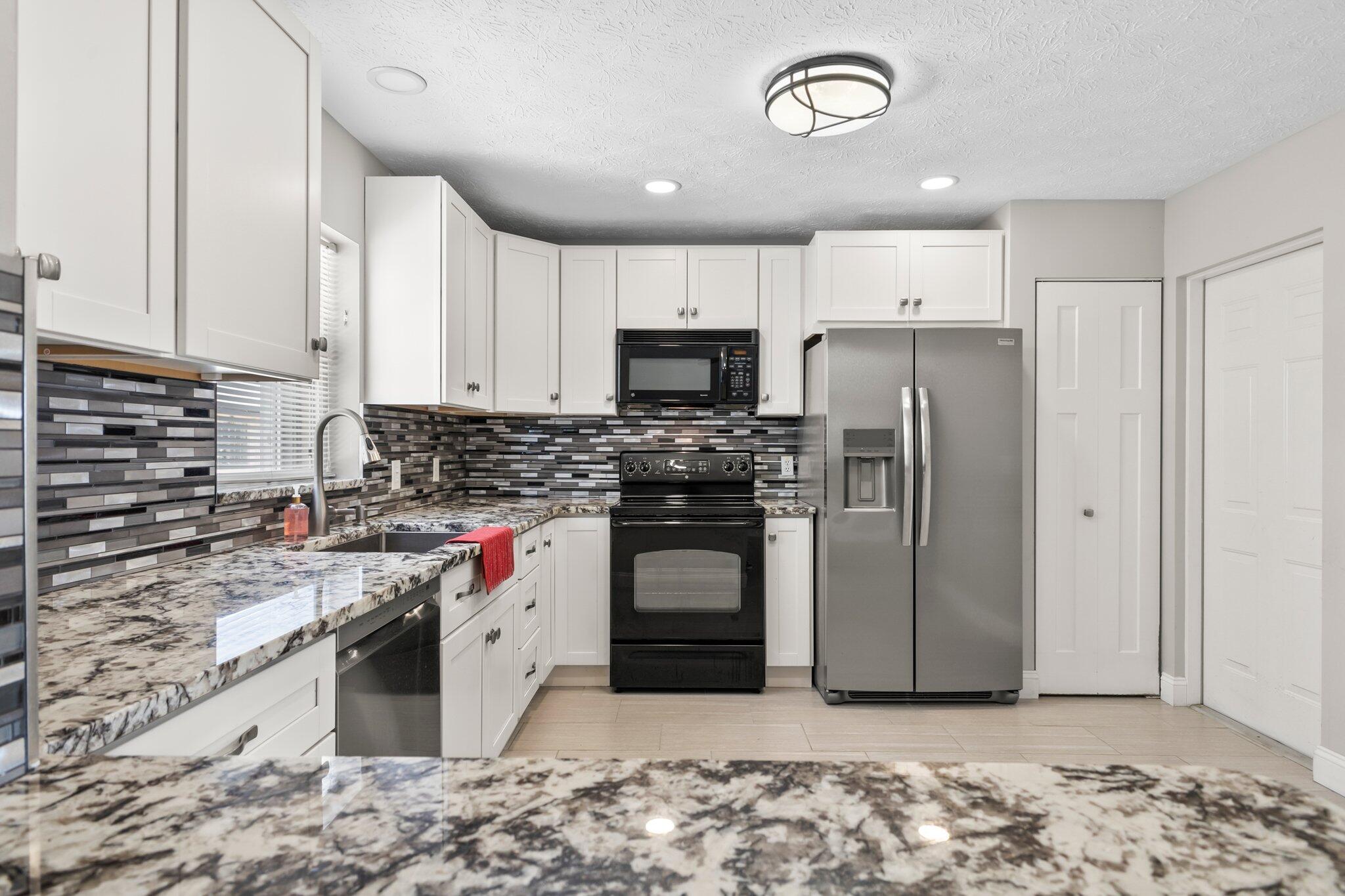 5712 Spindle Place Fort Pierce, FL 34982 - Photo 10 of 35 a kitchen with stainless steel appliances granite countertop a stove a sink and a refrigerator