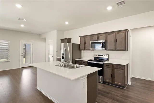 a kitchen with stainless steel appliances kitchen island granite countertop a sink stove and refrigerator