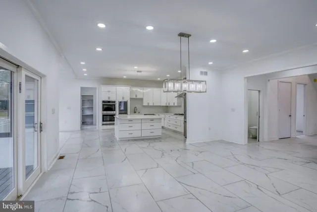 a large kitchen with stainless steel appliances kitchen island granite countertop a stove a sink and a refrigerator