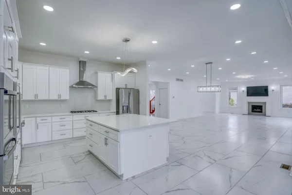 a large kitchen with stainless steel appliances a large counter top a stove and a refrigerator