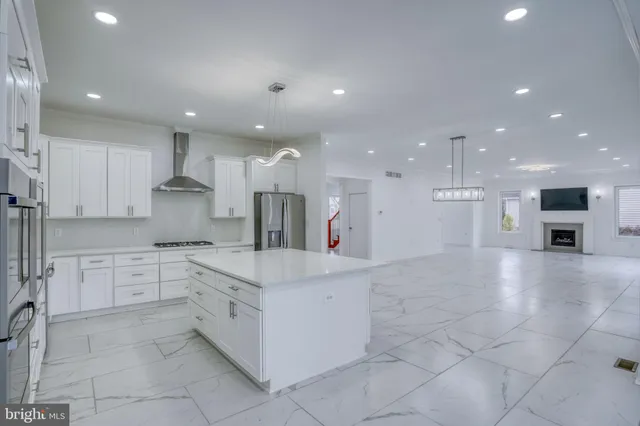 a large kitchen with stainless steel appliances a large counter top a stove and a refrigerator