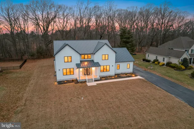 a view of a house with a yard and large trees