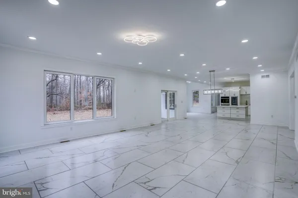 a view of empty room with kitchen and fireplace