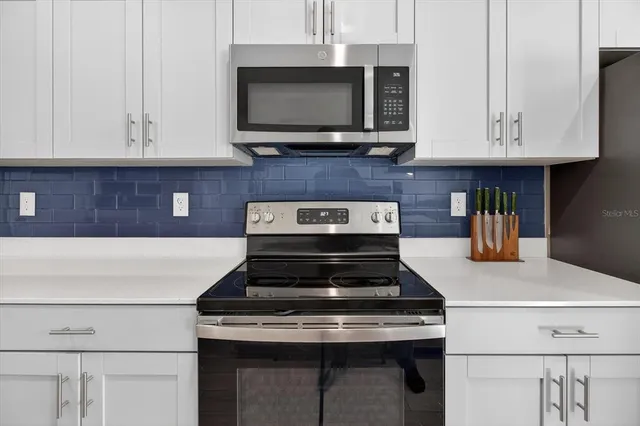 a kitchen with stainless steel appliances granite countertop a stove a sink and a microwave
