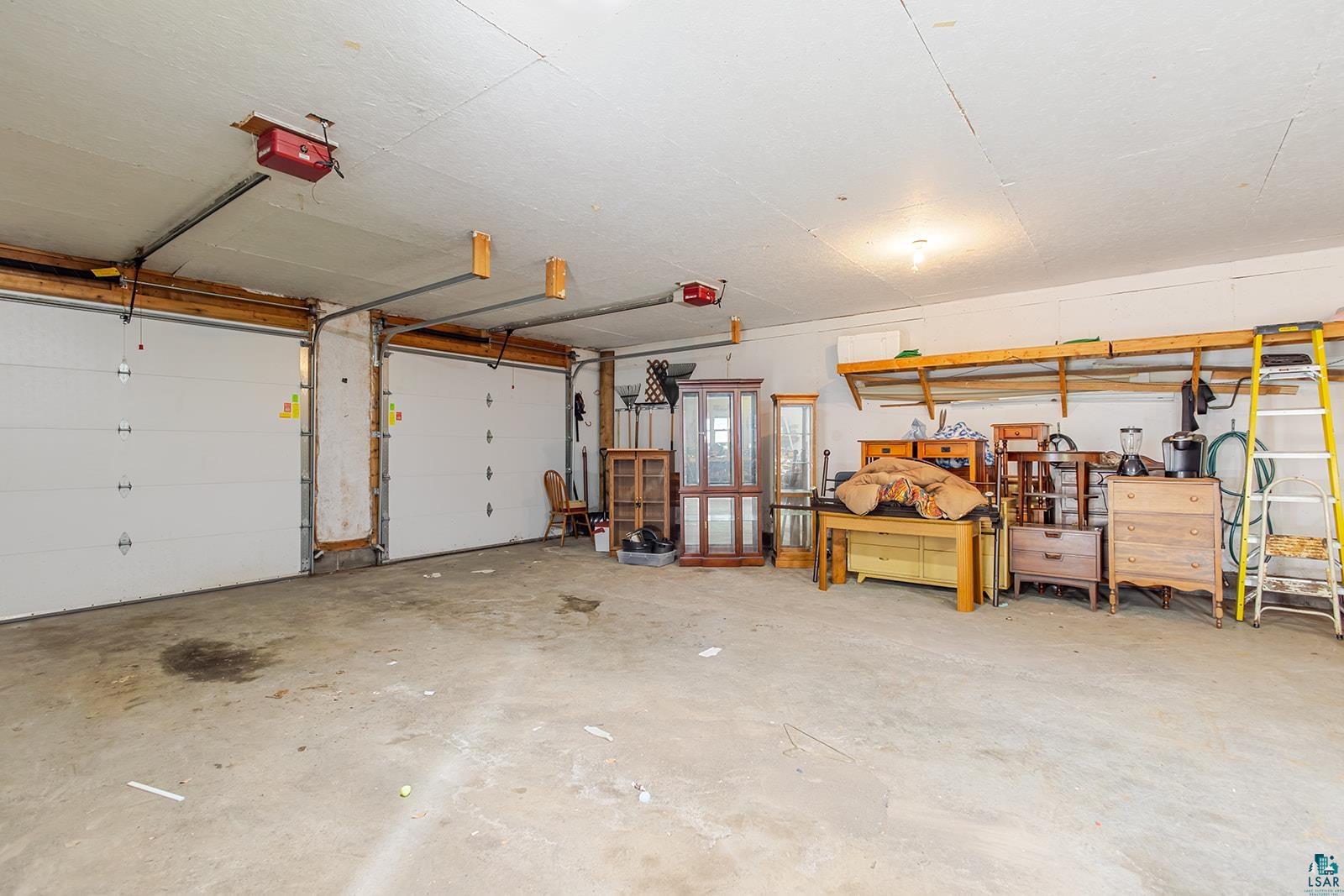 438 9th Street Cloquet, MN 55720 - Photo 27 of 27 Oversized 2 door garage. 2 vehicle depth, with concrete flooring, two white panel garage doors, and overhead storage shelving