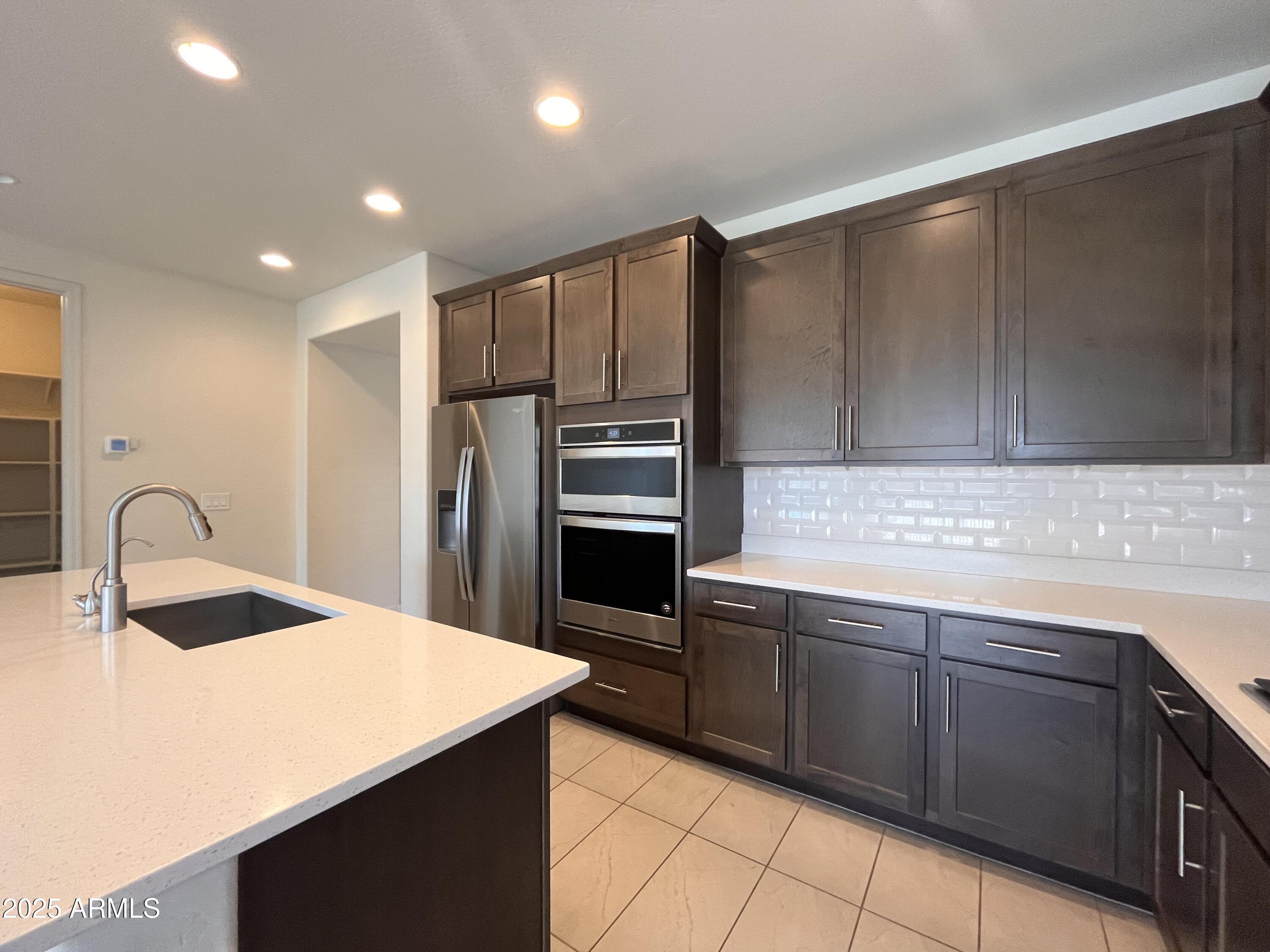 22857 East Marsh Road Queen Creek, AZ 85142 - Photo 15 of 38 a kitchen with stainless steel appliances a sink dishwasher a refrigerator and cabinets with wooden floor