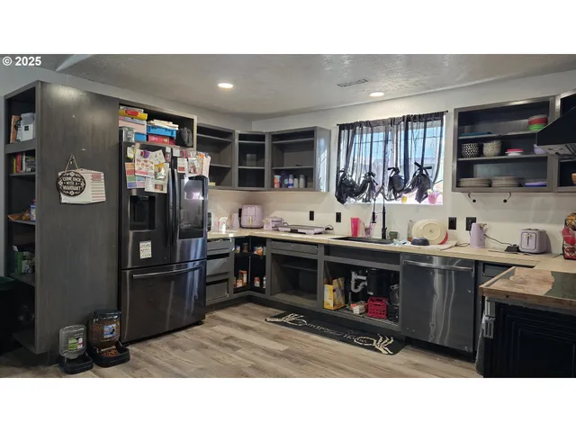 a kitchen with stainless steel appliances kitchen island granite countertop a refrigerator and cabinets