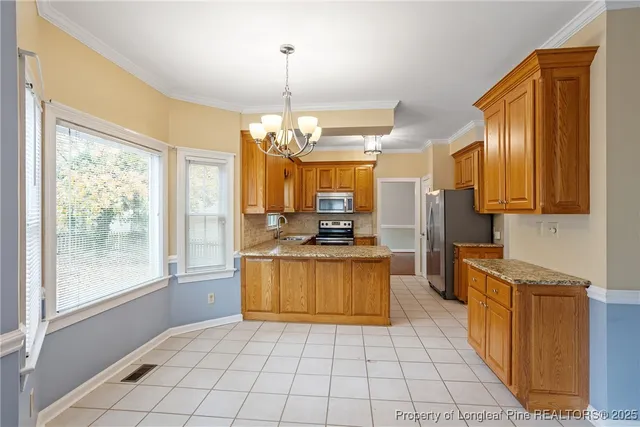 a large kitchen with kitchen island granite countertop a stove top oven a sink a counter space and cabinets