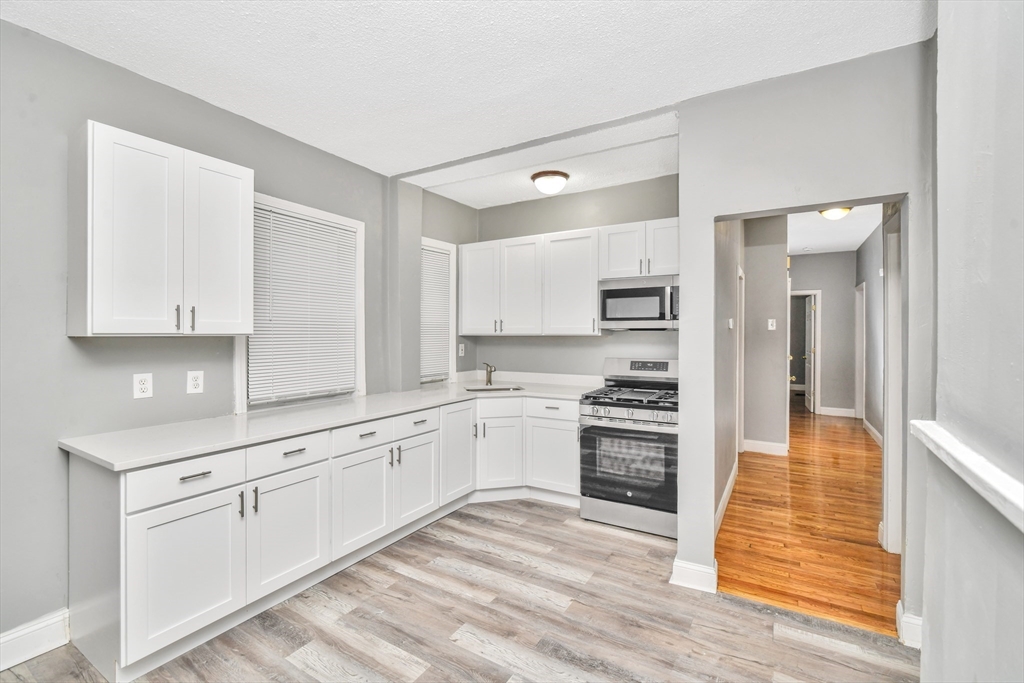 352 Norfolk Street, Unit 3 Boston, MA 02124 - Photo 2 of 12 a kitchen with granite countertop white cabinets and stainless steel appliances