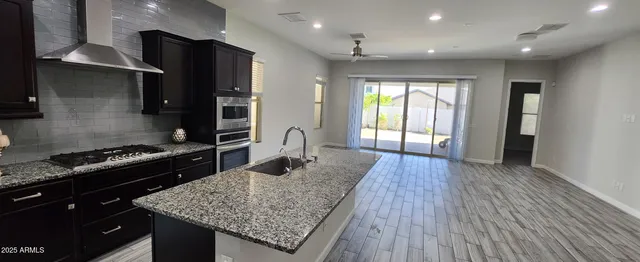 a kitchen with stainless steel appliances granite countertop a stove and a wooden floors
