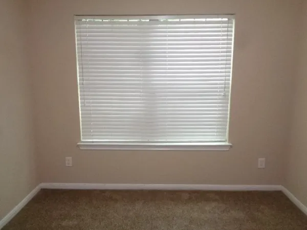 a view of an empty room with closet and mirror