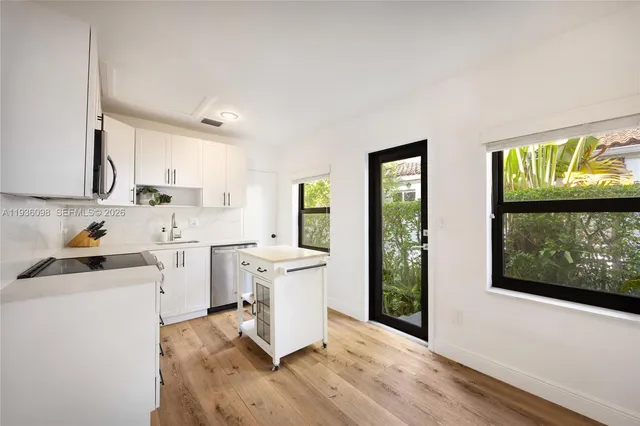 a room with a white cabinets a stove a sink and a window
