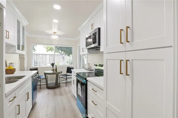 a kitchen with cabinets a sink a counter top space and living room view
