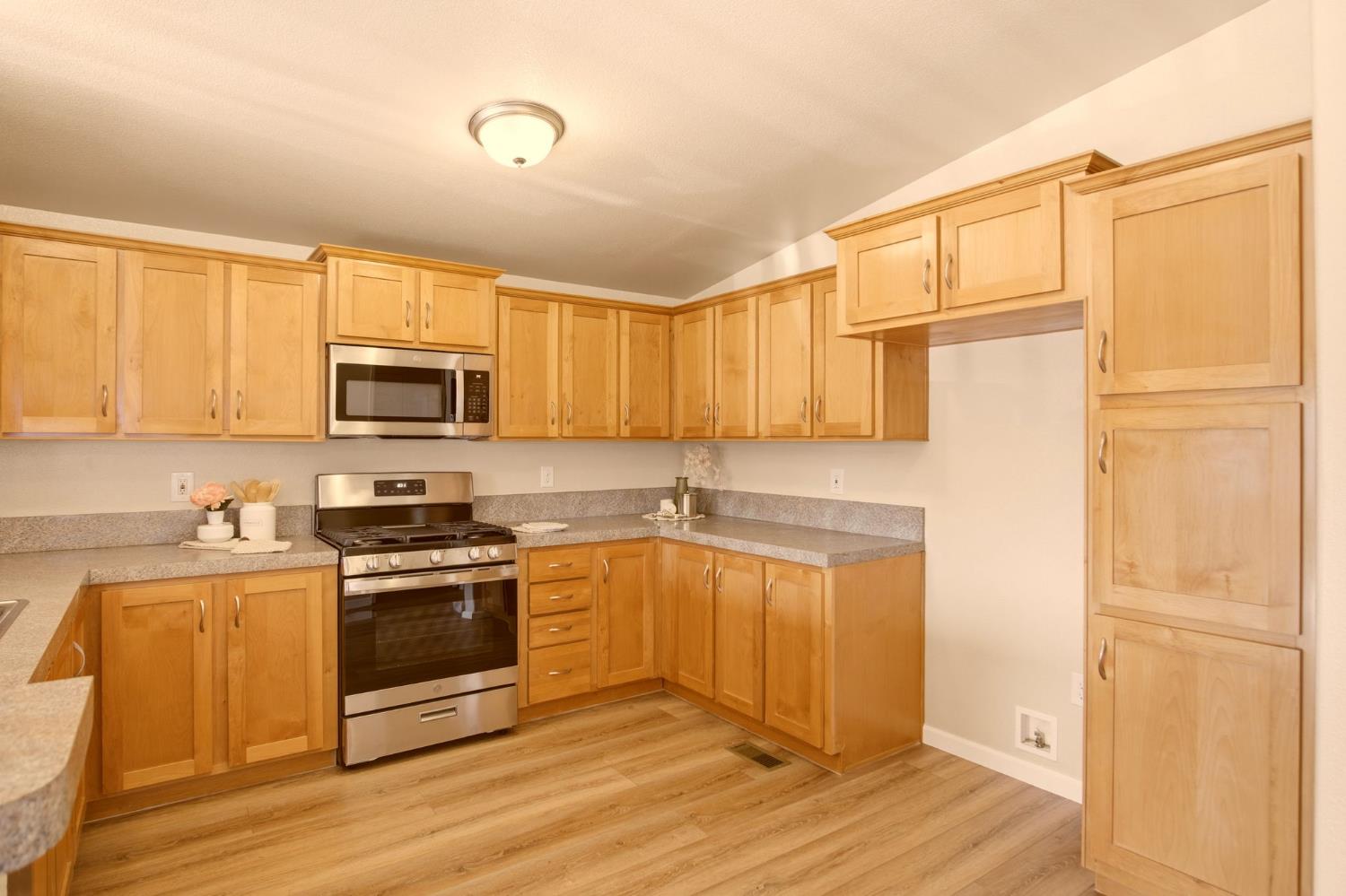 145 Dory Lane Modesto, CA 95356 - Photo 11 of 27 a kitchen with stainless steel appliances granite countertop a refrigerator a stove top oven a sink and dishwasher with wooden floor