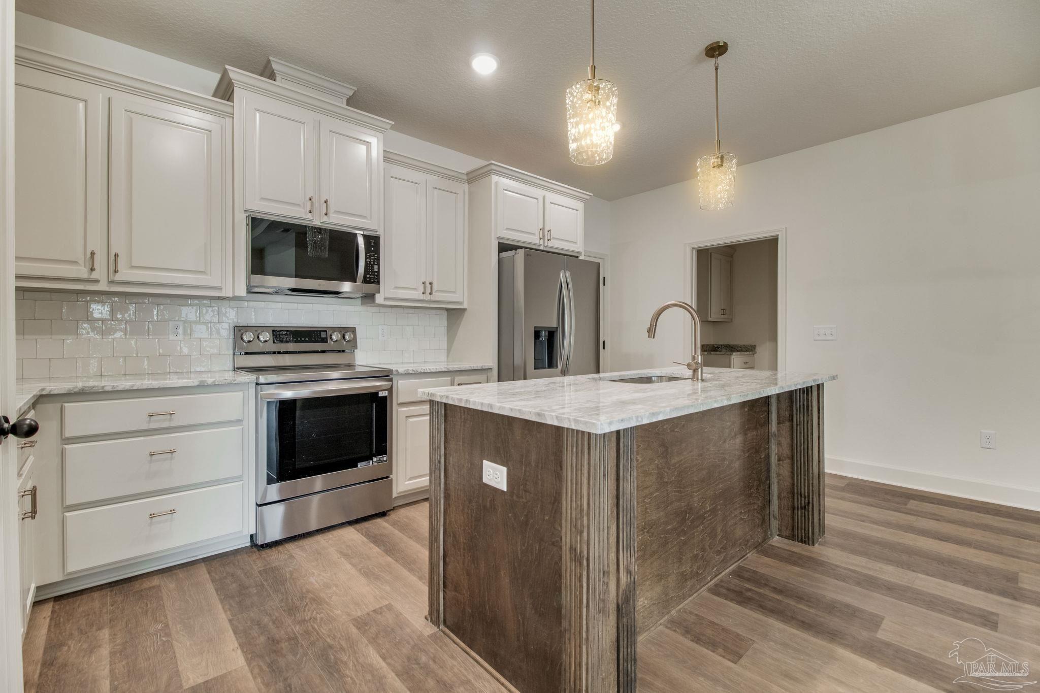 4310 Watkins Street Pace, FL 32571 - Photo 30 of 58 a kitchen with kitchen island a sink stainless steel appliances and cabinets